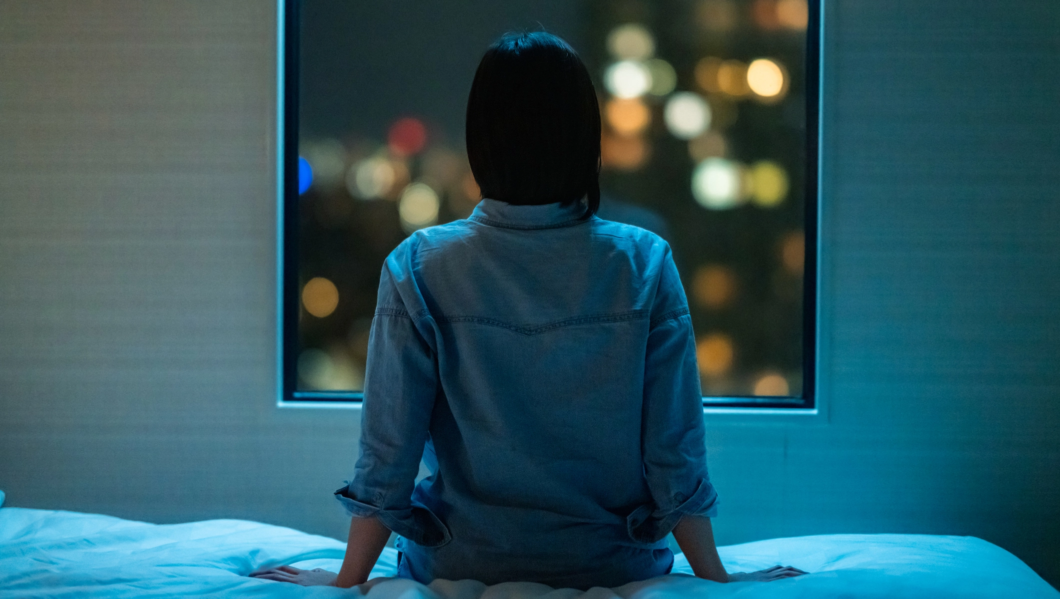 woman having anxiety at night looking out in the window